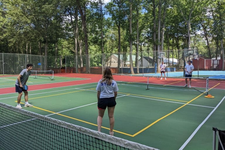 a person standing next to a net on a court with a racket